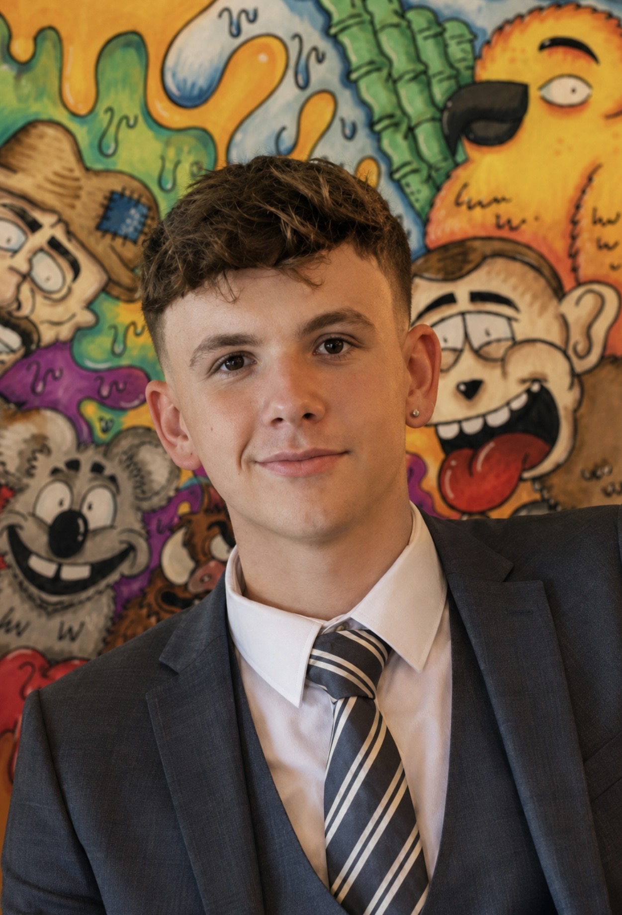 Charlie Cully photographed in front of one of his own hand-drawn character murals.