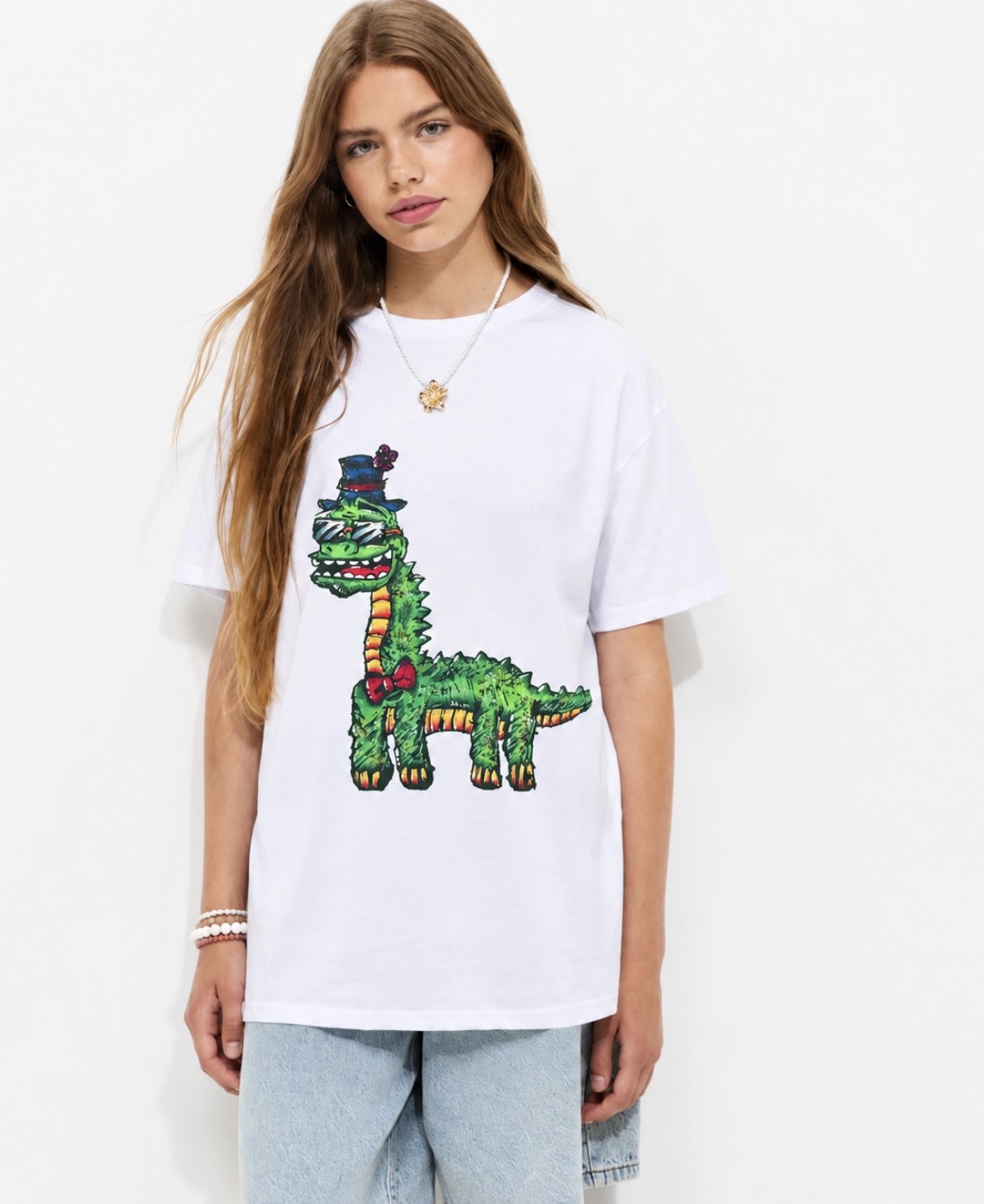 A woman wearing a white CC Illustrations t-shirt printed with a green dinosaur in a top hat and red bow tie.